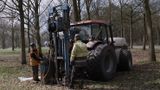 Twee mannen bij kleine tractor met boorinstallatie