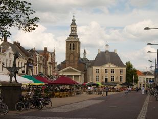 Volle terrassen onder grote parasols op de Markt in Roosendaal met uitzicht op de St Jan en het oude raadhuis
