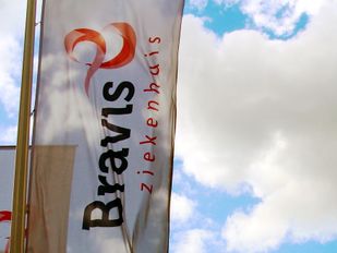 Witte banner met zwarte en rode tekst 'Bravis ziekenhuis' tegen een blauwe lucht en witte wolken
