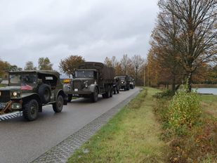 Legervoertuigen uit de Tweede Wereldoorlog rijden in colonne over polderweg