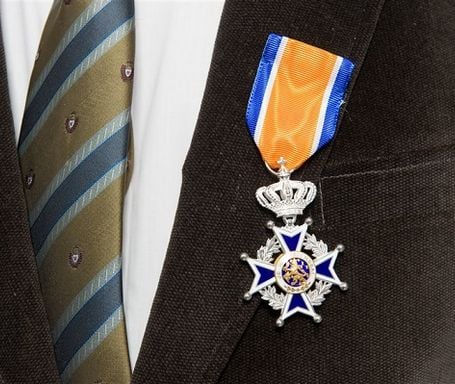Close-up van koninklijke onderscheiding opgespeld op het rever van een zwart colbert