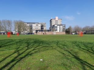 Foto van de voormalige kerk De Goede Herder in de wijk Langdonk met op de voorgrond het grasveld.