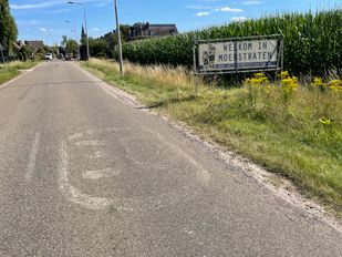 Vervaagd 30km-teken op asfalt en in de berm een spandoek met de tekst Welkom in Moerstraten