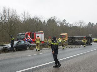 Ongeluk op de snelweg met auto tegen de vangrail en een bestelbus op z'n kant midden op de weg met er omheen hulpverleners van politie en brandweer