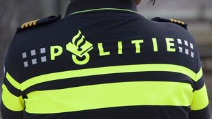 Close up van de rug van een politie-agent met fluoriscerende strepen en het logo van de politie