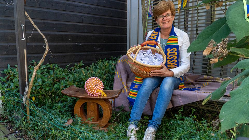 Annemieke de Bruijckere met naast haar een chief-stoel van haar vader, om haar nek een traditionele sjaal en in haar handen een mand vol goodies.