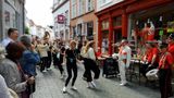 Publiek kijkt lachend toe als straatorkest en danseressen door smalle straat van Bergen op Zoom trekken