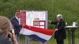 Patrick van der Velden en Ans van den Berg staan aan weerzijden van een informatiepaneel en onthullen deze door het weghalen van de Nederlandse vlag