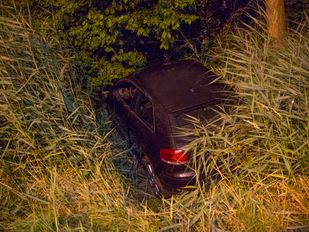 Zwarte auto overdwars in sloot