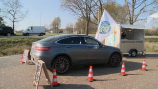 Auto rijdt tussen pionnen door naar verkoopkraam in drive-through