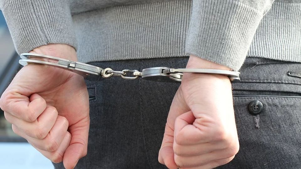 Close-up van handen die op de rug in handboeien zitten