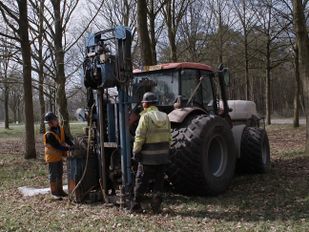 Twee mannen bij kleine tractor met boorinstallatie