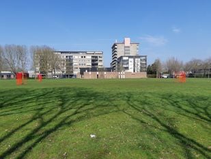Foto van de voormalige kerk De Goede Herder in de wijk Langdonk met op de voorgrond het grasveld.
