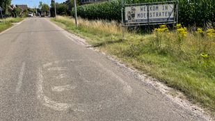 Vervaagd 30km-teken op asfalt en in de berm een spandoek met de tekst Welkom in Moerstraten