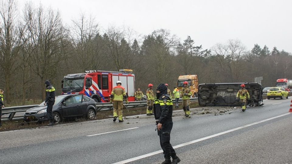 Ongeluk op de snelweg met auto tegen de vangrail en een bestelbus op z'n kant midden op de weg met er omheen hulpverleners van politie en brandweer