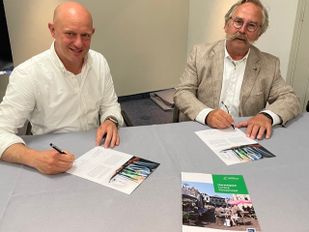 Koen Bakker van Koninklijke Horeca Nederland Roosendaal ondertekent een formulier en rechts naast hem kijkt wethouder Cees Lok toe