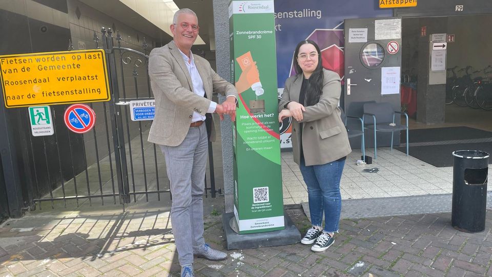 Wethouder René van Ginderen en GroenLinks raadslid Chahira Mediani nemen de eerste zonnebrandpaal in Roosendaal in gebruik.