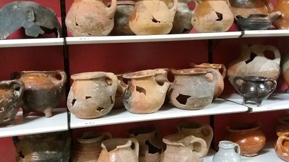 Plankenkast gevuld met archeologische vondsten zoals oude potten
