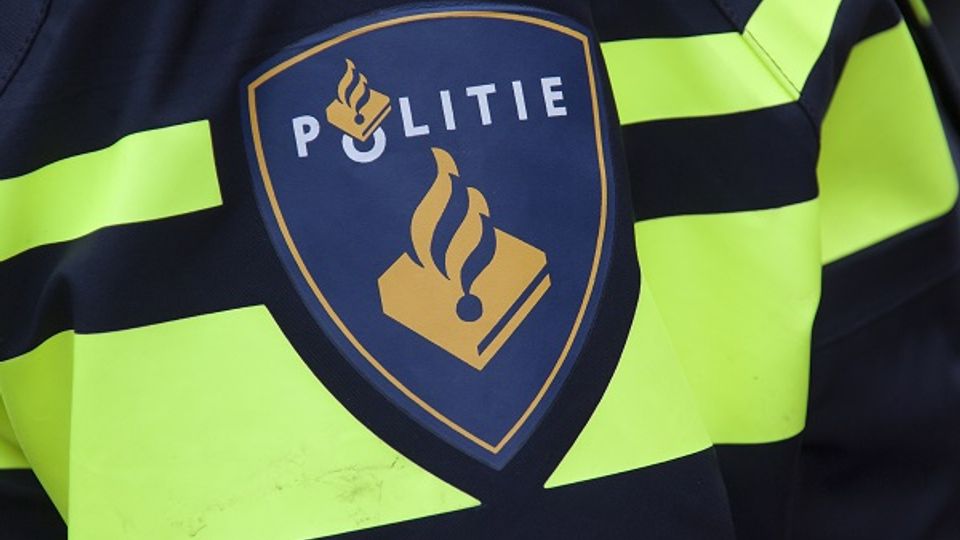 Close up van politie-embleem op zwart uniform met twee reflecterend gele strepen