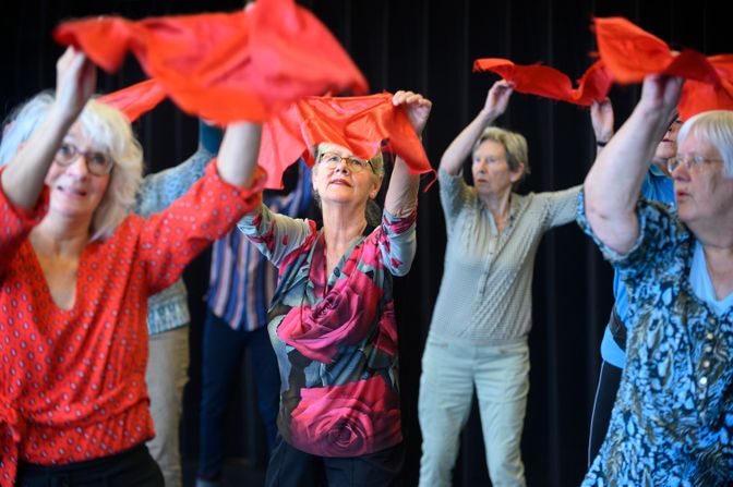 Senioren dansen met rode doeken boven het hoofd