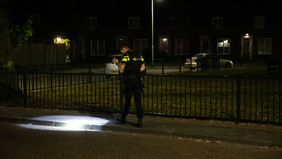 Agent zoekt in het donker naar bewijs en richt zaklamp op de stoep