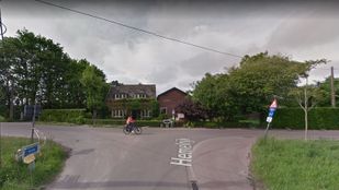 Fietser steekt vanaf links een t-splitsing over met op de achtergrond een woning