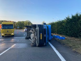 Gele bergingswagen staat naast een blauwe bestelbus die op z'n kant ligt