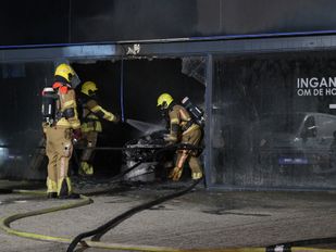 Auto in bedrijfspand vat vlam, brandweer schaalt groots op