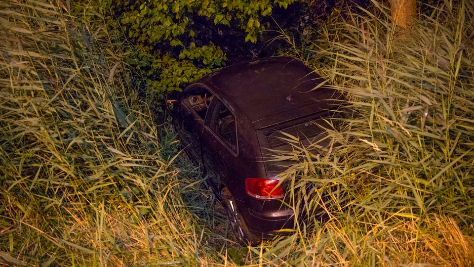 Zwarte auto overdwars in sloot