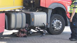 Politieagent staat naast een vrachtwagen waaronder een klemgereden fiets ligt