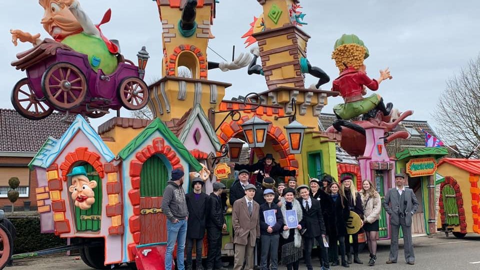Verklede leden van bouwclub Hoevekestijn poseren voor hun felgekleurde carnavalswagen