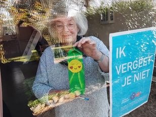 Deelnemer aan 'Ik vergeet je niet' 2020 laat vanachter haar raam haar zelfgemaakte kunstwerk zien