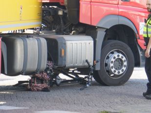 Politieagent staat naast een vrachtwagen waaronder een klemgereden fiets ligt
