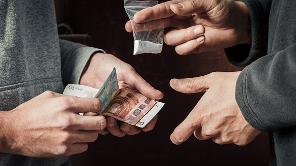Close-up van drugsdeal tussen twee mensen waarbij je alleen de handen ziet en geld wordt betaald voor een zakje drugs
