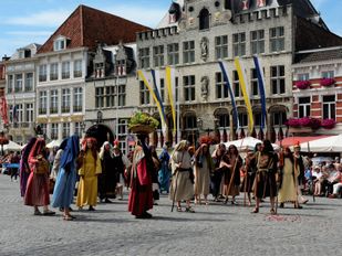 Historisch geklede mensen in stoet over de Grote Markt in Bergen op Zoom voor de Maria Ommegang