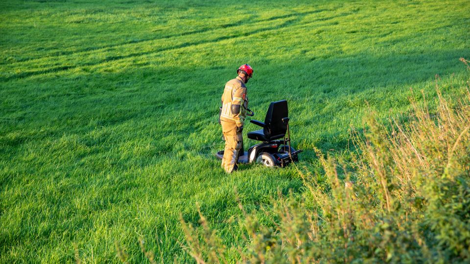 Vrouw rijdt met scootmobiel van dijk in Standdaarbuiten