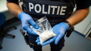 Stockfoto van een politieagent met blauwe handschoenen en een zakje drugs