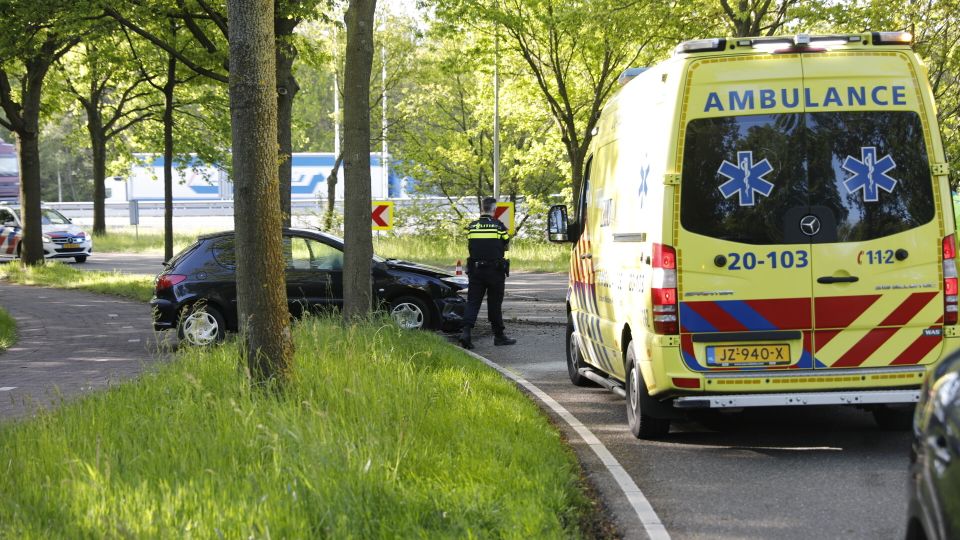 Ambulance staat geparkeerd naast een auto die tegen een boom is gereden
