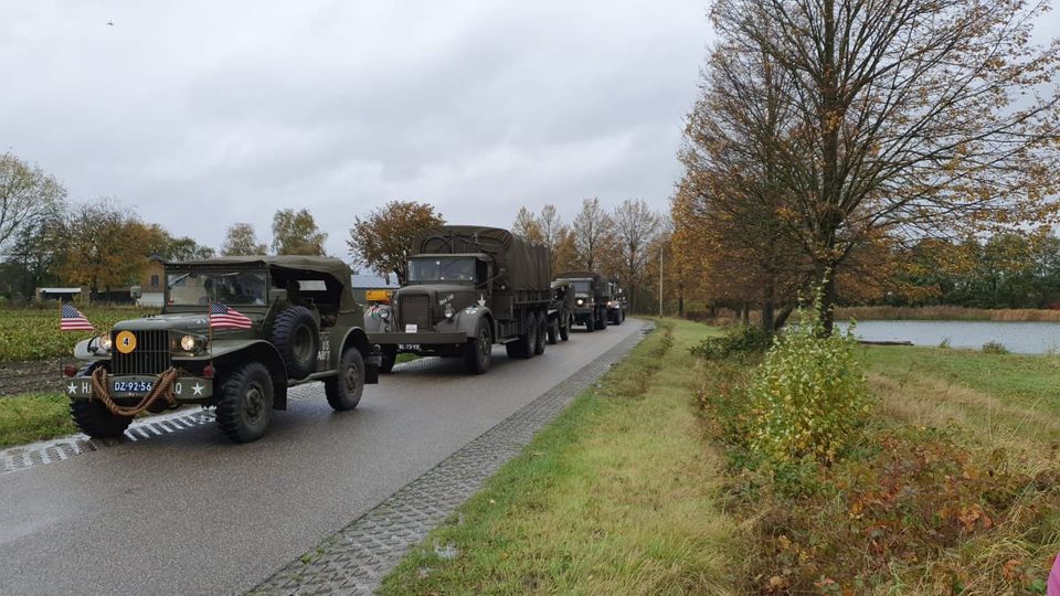 Legervoertuigen uit de Tweede Wereldoorlog rijden in colonne over polderweg