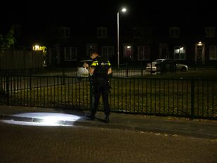 Agent zoekt in het donker naar bewijs en richt zaklamp op de stoep