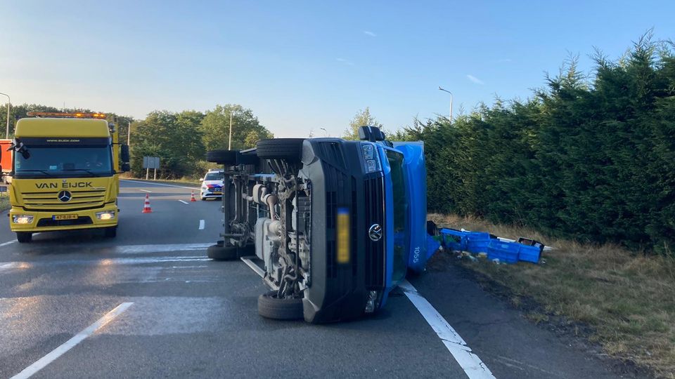 Gele bergingswagen staat naast een blauwe bestelbus die op z'n kant ligt