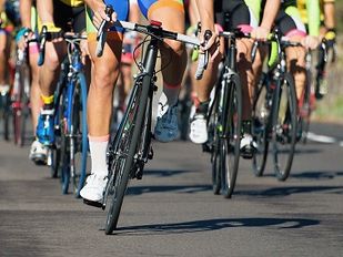 Close-up van wielrennersbenen en racefietsbanden die als groep over asfalt rijden