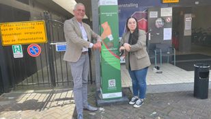 Wethouder René van Ginderen en GroenLinks raadslid Chahira Mediani nemen de eerste zonnebrandpaal in Roosendaal in gebruik.