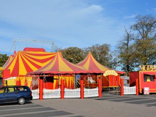 Rood-geel gestreepte kermistent, -kassa en -wagens