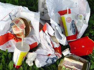 Afvalstapel van gebruikte fastfoodverpakkingen zoals hamburgerdoosjes en milkshakebekers met rietjes