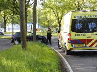 Ambulance staat geparkeerd naast een auto die tegen een boom is gereden