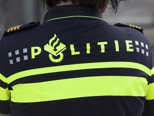 Close up van de rug van een politie-agent met fluoriscerende strepen en het logo van de politie