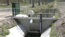 Stuw Nieuwe Dreef in Wouwse Plantage met op achtergrond een volle sloot en op voorgrond de droge sloot