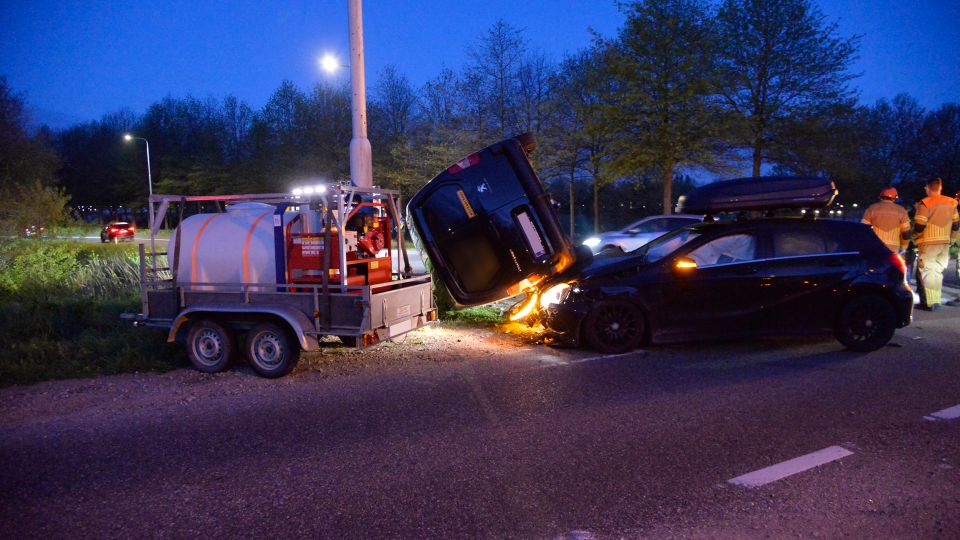 Auto en busje botsen, busje komt op zijkant tegen paal terecht