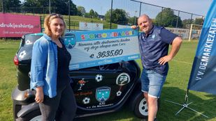 Leon Oomen en Sandra Jongenelen van voetbalvereniging SJO De Markiezaten in Bergen op Zoom staan naast een grote kartonnen cheque ter waarde van €3635,60
